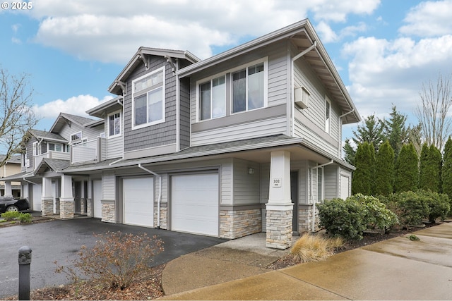 view of front of house featuring an attached garage, aphalt driveway, and stone siding