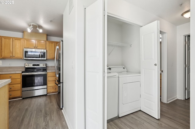 interior space featuring washer and dryer, laundry area, baseboards, and wood finished floors