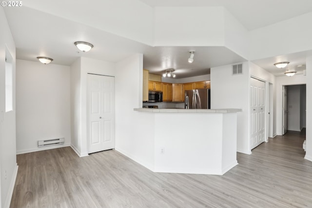kitchen featuring visible vents, light wood-style floors, light countertops, a baseboard radiator, and stainless steel appliances