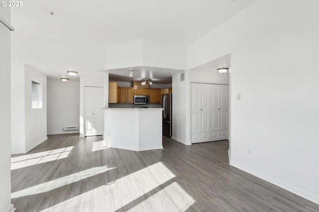 unfurnished living room featuring a sink, baseboards, visible vents, and wood finished floors