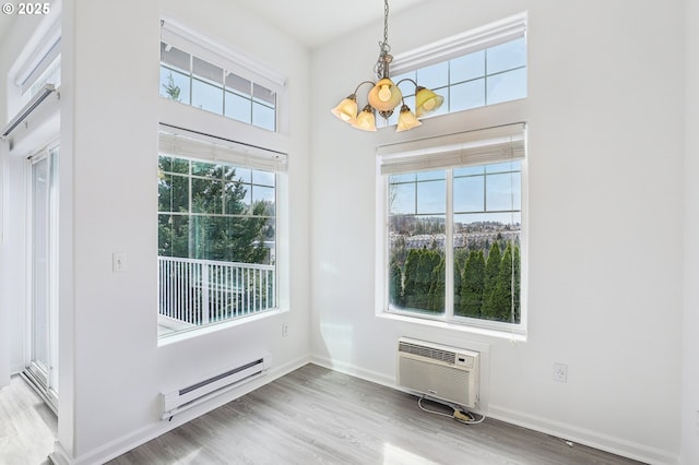 entryway featuring wood finished floors, baseboards, a baseboard radiator, an AC wall unit, and a chandelier