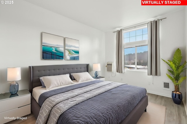bedroom featuring baseboards, visible vents, and wood finished floors