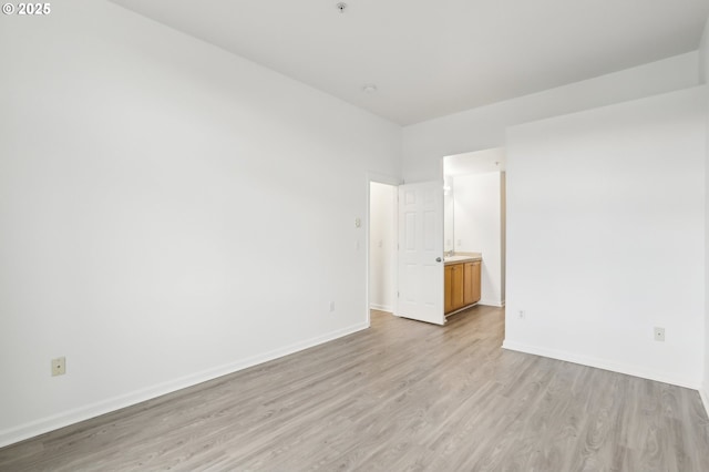 spare room with baseboards and light wood-style flooring