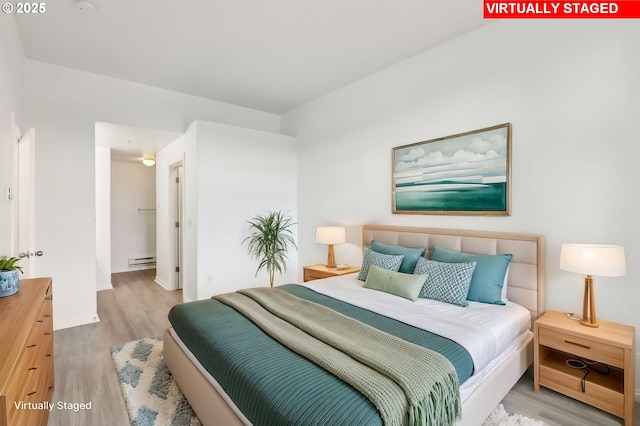 bedroom featuring baseboards, wood finished floors, and baseboard heating