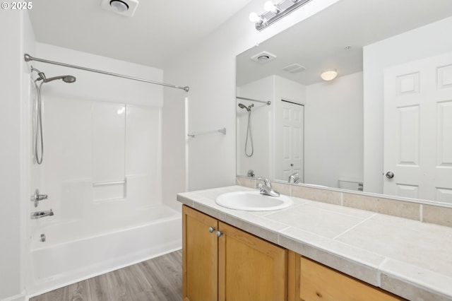 bathroom featuring vanity, visible vents, tub / shower combination, wood finished floors, and toilet