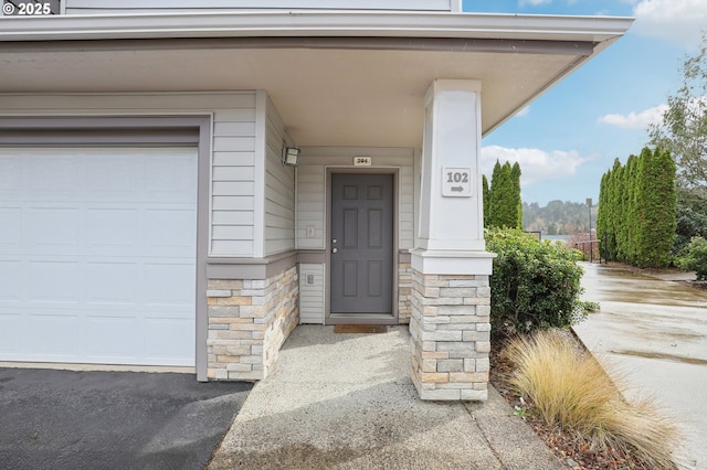 property entrance featuring a garage and stone siding