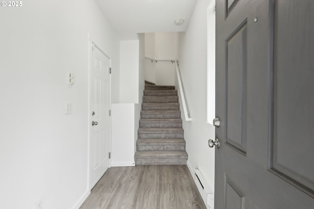 foyer entrance featuring stairway, baseboards, a baseboard radiator, and light wood-type flooring