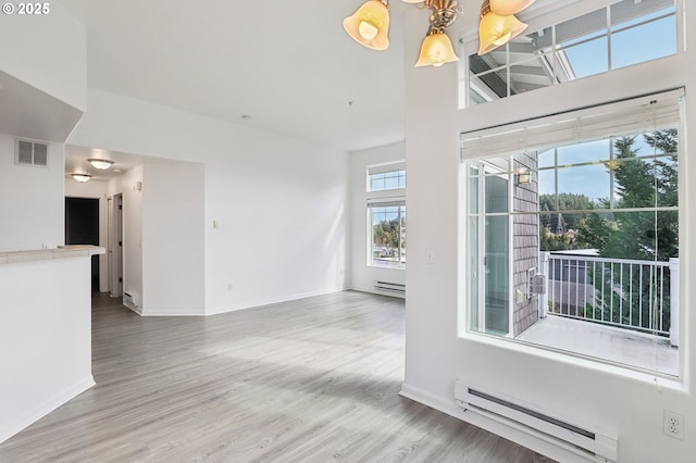 interior space with a baseboard heating unit, visible vents, baseboard heating, and wood finished floors