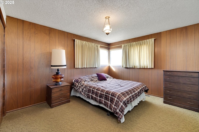 bedroom with wood walls, a textured ceiling, and carpet flooring