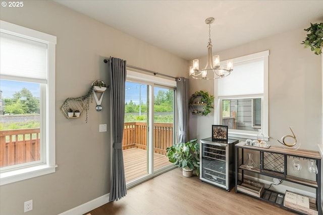 doorway with a chandelier, beverage cooler, wood finished floors, and baseboards