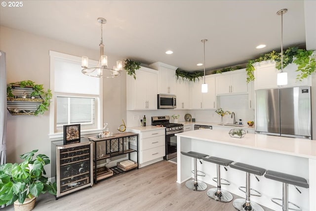 kitchen with appliances with stainless steel finishes, a sink, light countertops, decorative backsplash, and white cabinetry