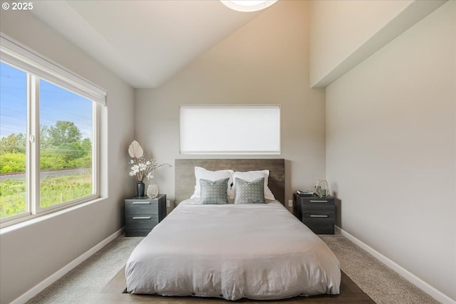 carpeted bedroom with multiple windows, lofted ceiling, and baseboards