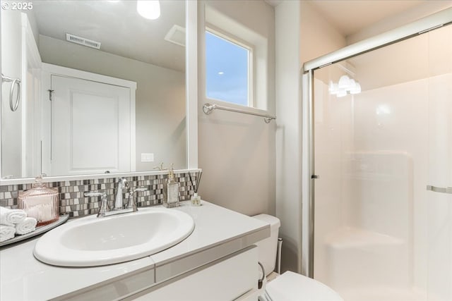 full bath featuring a stall shower, vanity, toilet, and tasteful backsplash
