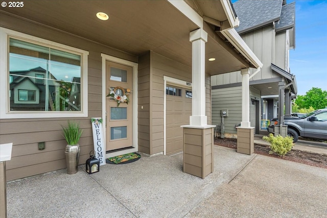 view of exterior entry with a shingled roof, a garage, and board and batten siding
