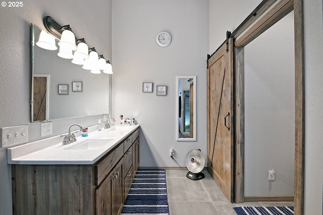 bathroom with double vanity, tile patterned floors, baseboards, and a sink