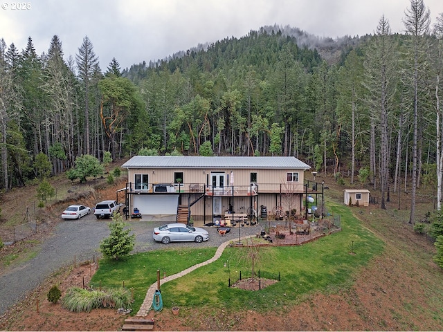 rear view of house featuring a garage, a deck, and a yard