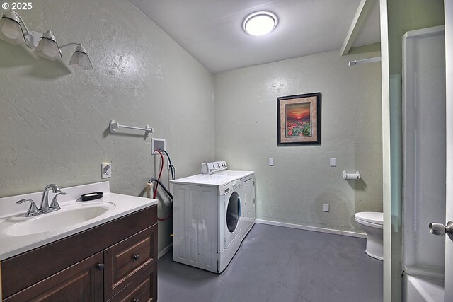 clothes washing area with laundry area, washer and dryer, a textured wall, and a sink