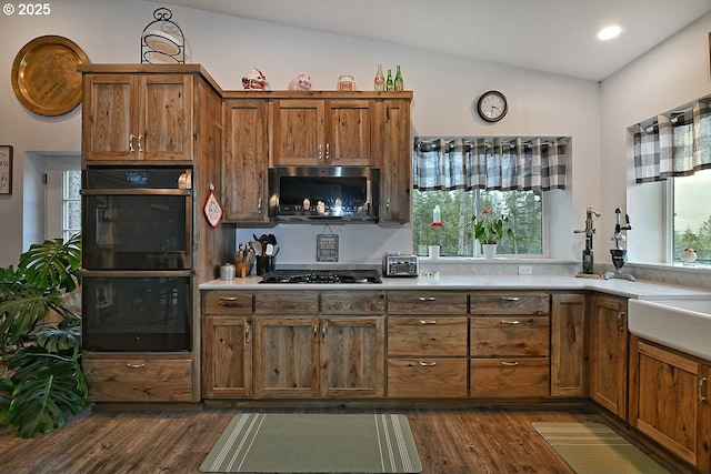 kitchen featuring double oven, dark hardwood / wood-style floors, lofted ceiling, and stainless steel gas stovetop