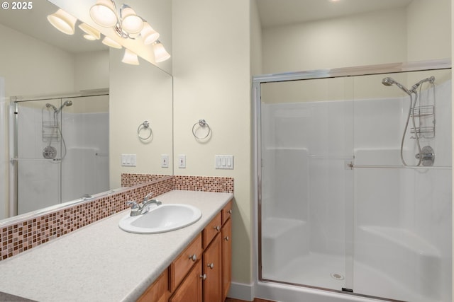 bathroom featuring a shower with door, tasteful backsplash, and vanity