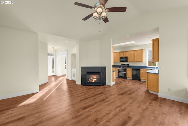 unfurnished living room with ceiling fan, lofted ceiling, a fireplace, and light hardwood / wood-style flooring