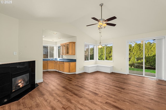 unfurnished living room featuring ceiling fan, dark hardwood / wood-style floors, lofted ceiling, and a fireplace