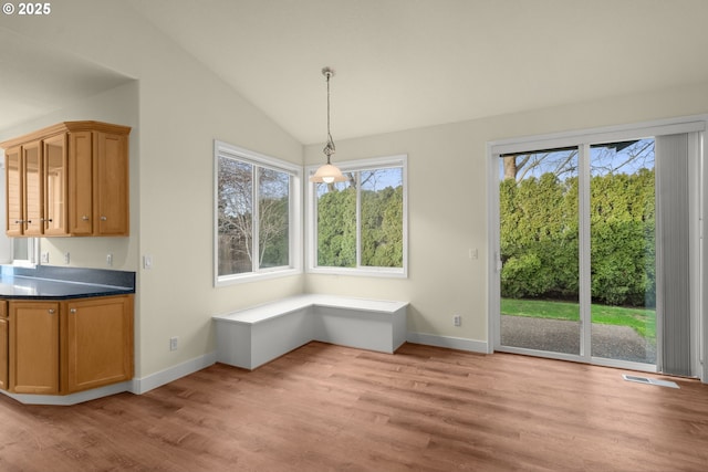 unfurnished dining area with light hardwood / wood-style flooring and vaulted ceiling