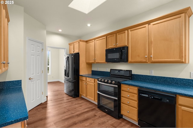 kitchen featuring wood-type flooring, black appliances, and a skylight