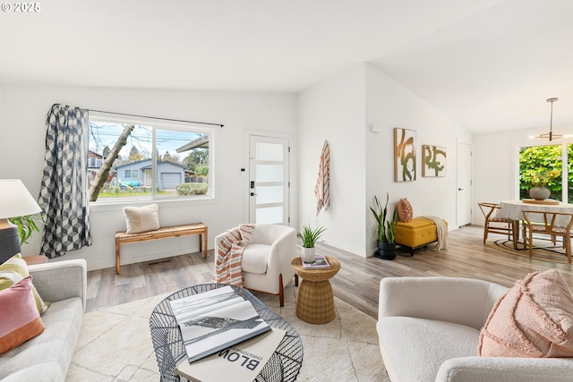 living room with light wood-type flooring, vaulted ceiling, and baseboards