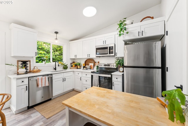 kitchen with stainless steel appliances, lofted ceiling, butcher block countertops, light wood-type flooring, and white cabinetry