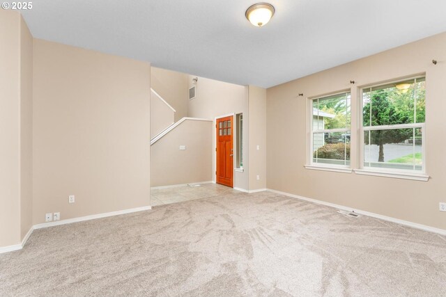 spare room with light carpet, visible vents, and baseboards