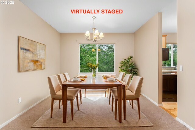 dining space featuring light carpet, baseboards, and a chandelier