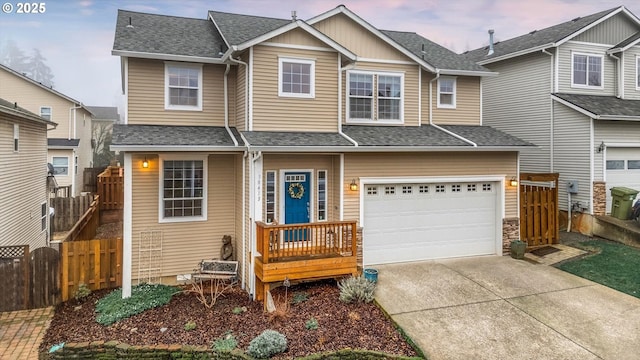 view of front of home featuring concrete driveway, roof with shingles, fence, and an attached garage