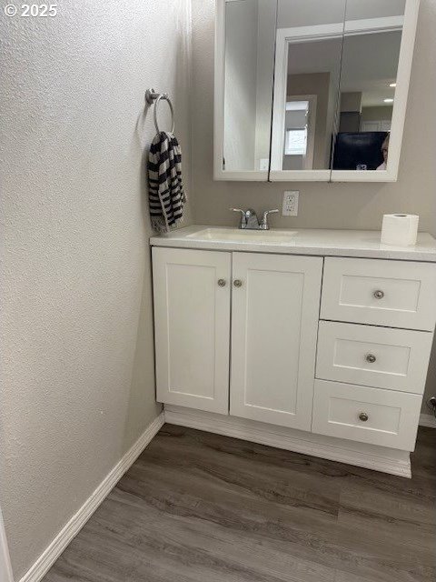 767 32nd Ave, Longview, WA 98632 - bathroom featuring vanity, baseboards, wood finished floors, and a textured wall