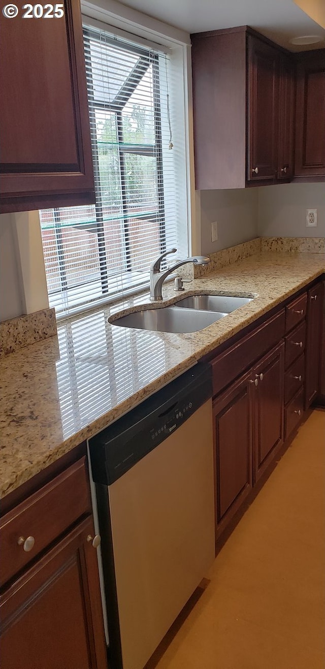 kitchen featuring dishwasher, a sink, and light stone counters