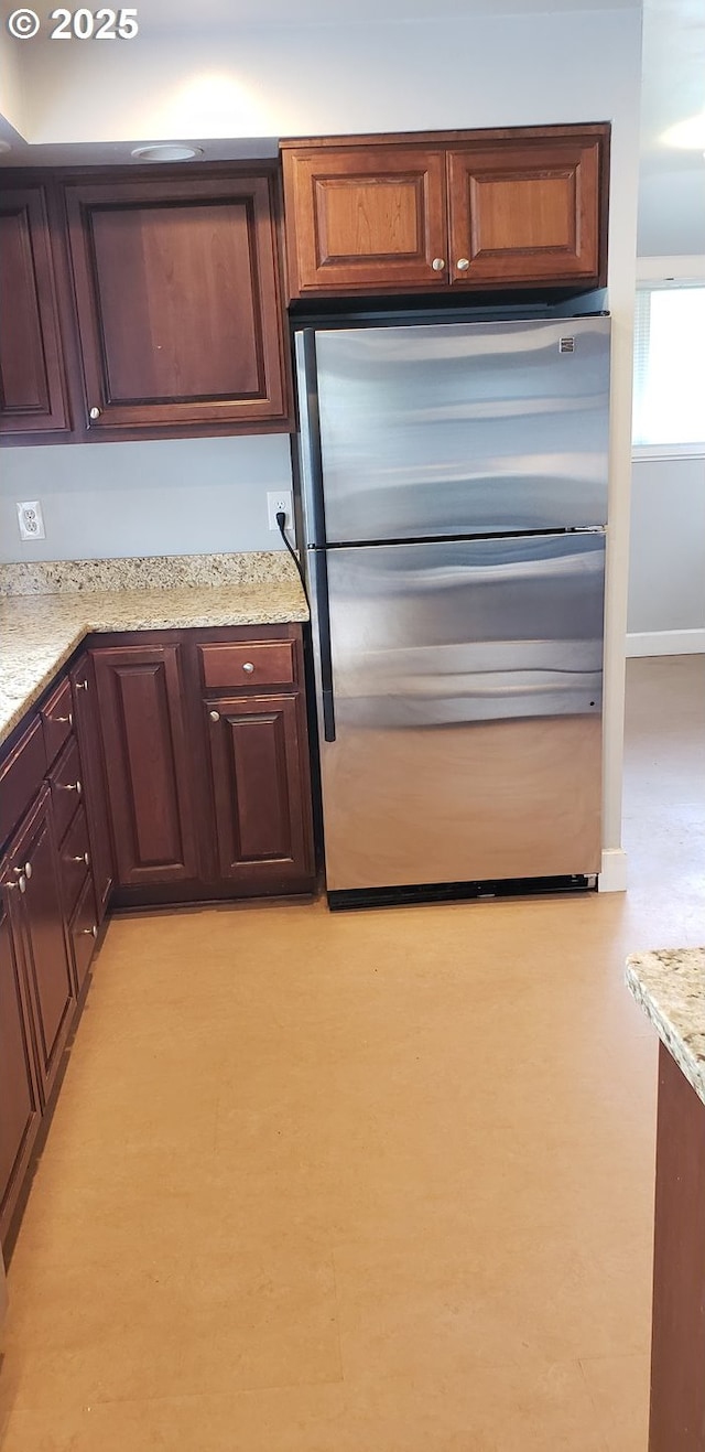 kitchen featuring freestanding refrigerator and light stone counters