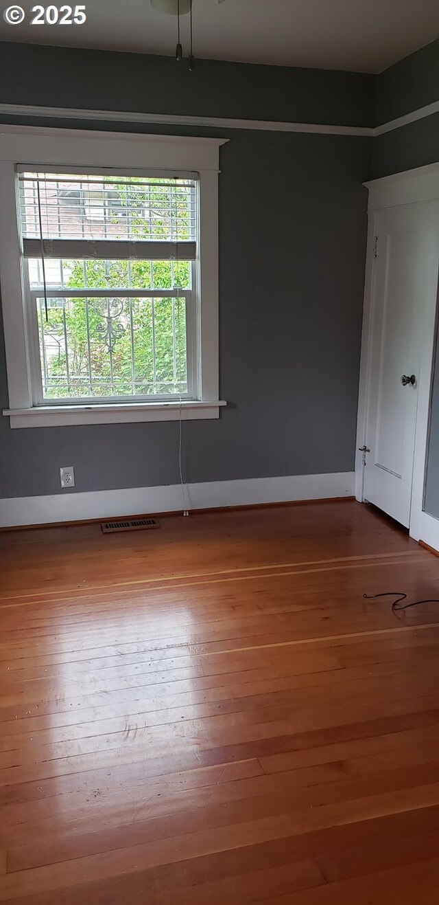 spare room featuring healthy amount of natural light, wood finished floors, and baseboards