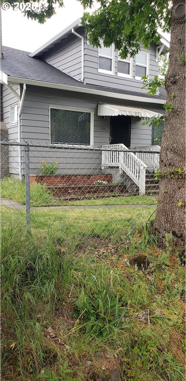 view of front of house with fence and a shingled roof