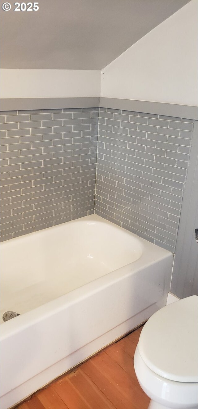 bathroom with wood finished floors, a tub, and toilet