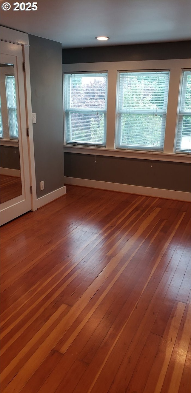 empty room with baseboards, hardwood / wood-style flooring, and plenty of natural light