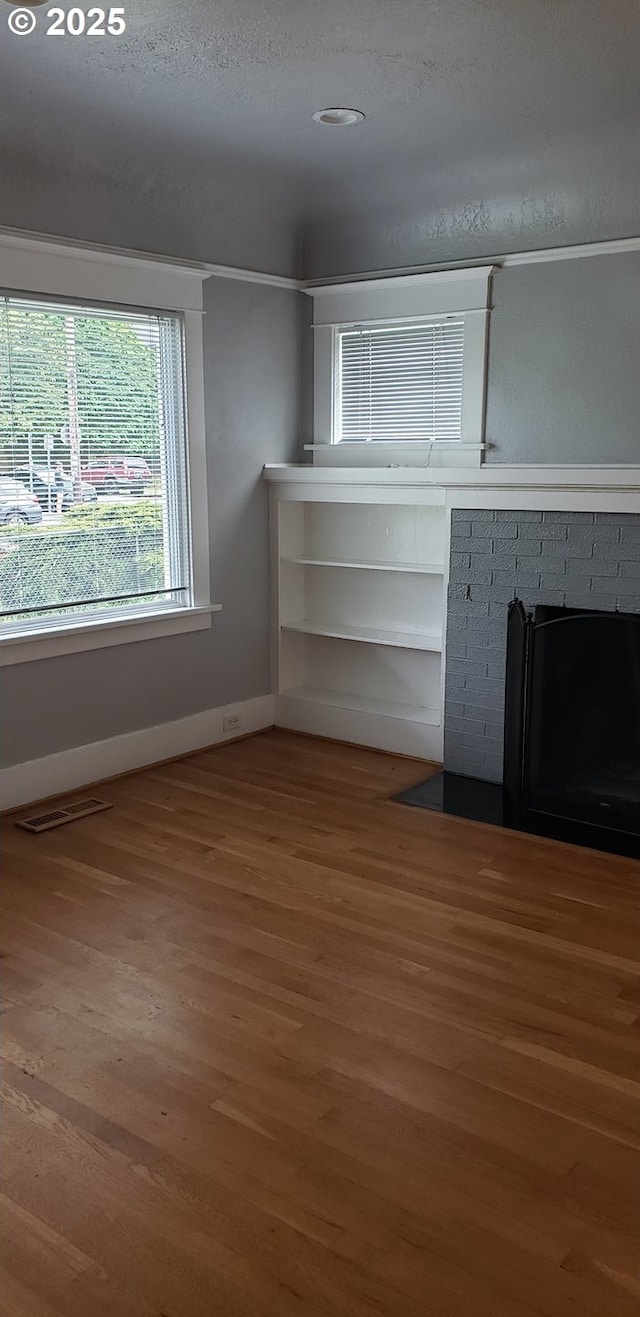 unfurnished living room with wood finished floors, baseboards, and a fireplace