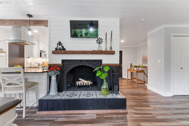 living room featuring a large fireplace, crown molding, baseboards, and wood finished floors