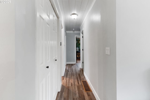 corridor with ornamental molding, visible vents, dark wood finished floors, and baseboards