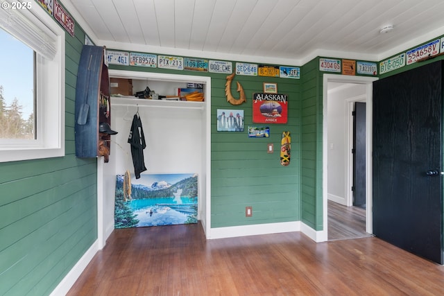 bedroom featuring a closet, wooden ceiling, wood walls, and wood finished floors