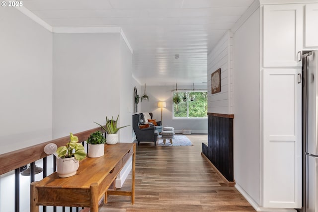 hall featuring ornamental molding, baseboards, and wood finished floors