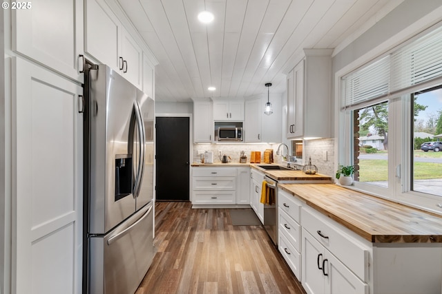 kitchen with a sink, stainless steel appliances, wood counters, and decorative backsplash