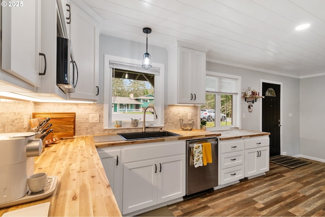 kitchen with appliances with stainless steel finishes, dark wood-type flooring, white cabinets, a sink, and wood counters