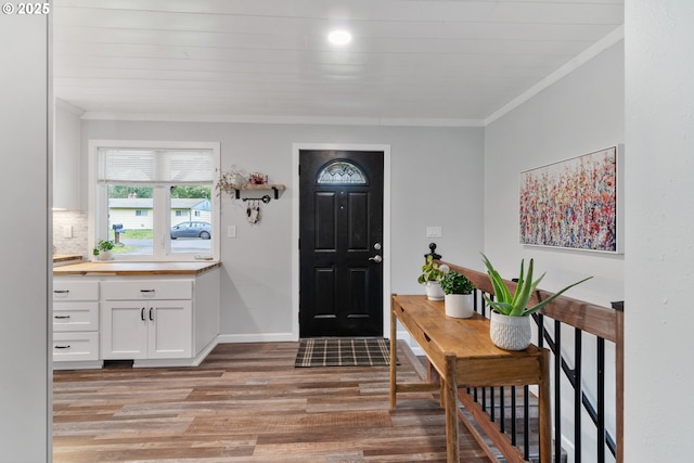 foyer entrance featuring crown molding, light wood-style flooring, and baseboards