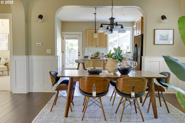 7010 N Kellogg St, Portland, OR 97203 - dining space with arched walkways, a wainscoted wall, a decorative wall, plenty of natural light, and a chandelier