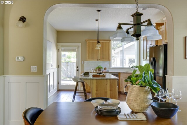 7010 N Kellogg St, Portland, OR 97203 - kitchen featuring arched walkways, freestanding refrigerator, plenty of natural light, a sink, and a wainscoted wall