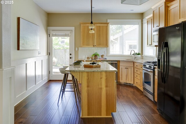 7010 N Kellogg St, Portland, OR 97203 - kitchen with black refrigerator with ice dispenser, stainless steel range with gas stovetop, a sink, light brown cabinets, and plenty of natural light